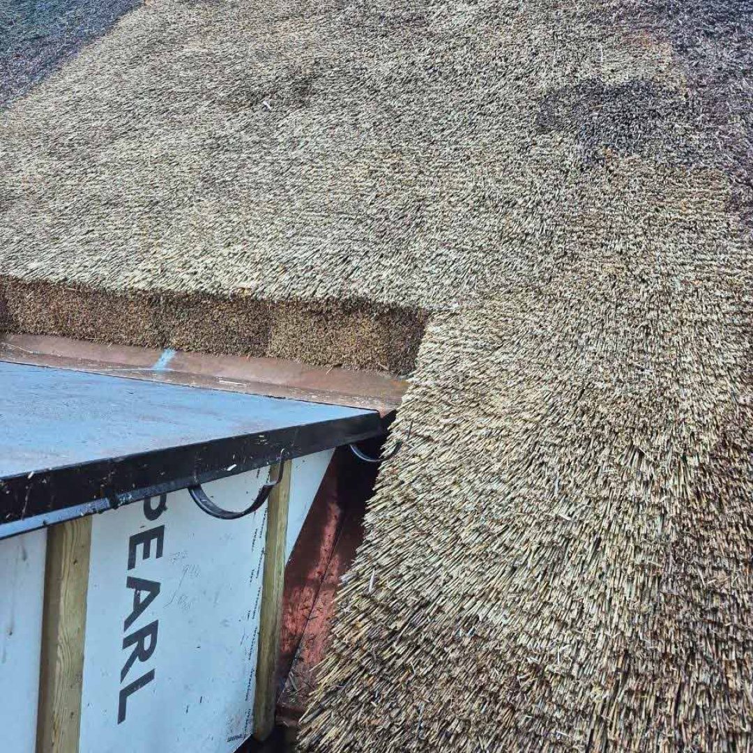 Kontrast mellem gammelt, mørkt strå og nyligt tækket, lyst strå på et repareret tag.